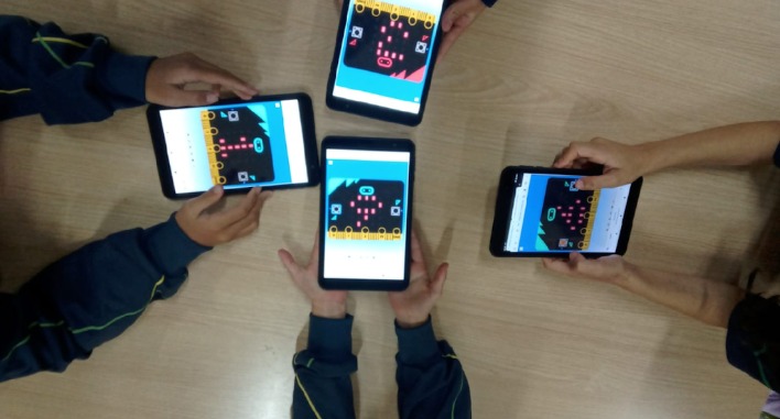 Crianças segurando vários tablets com um jogo na tela