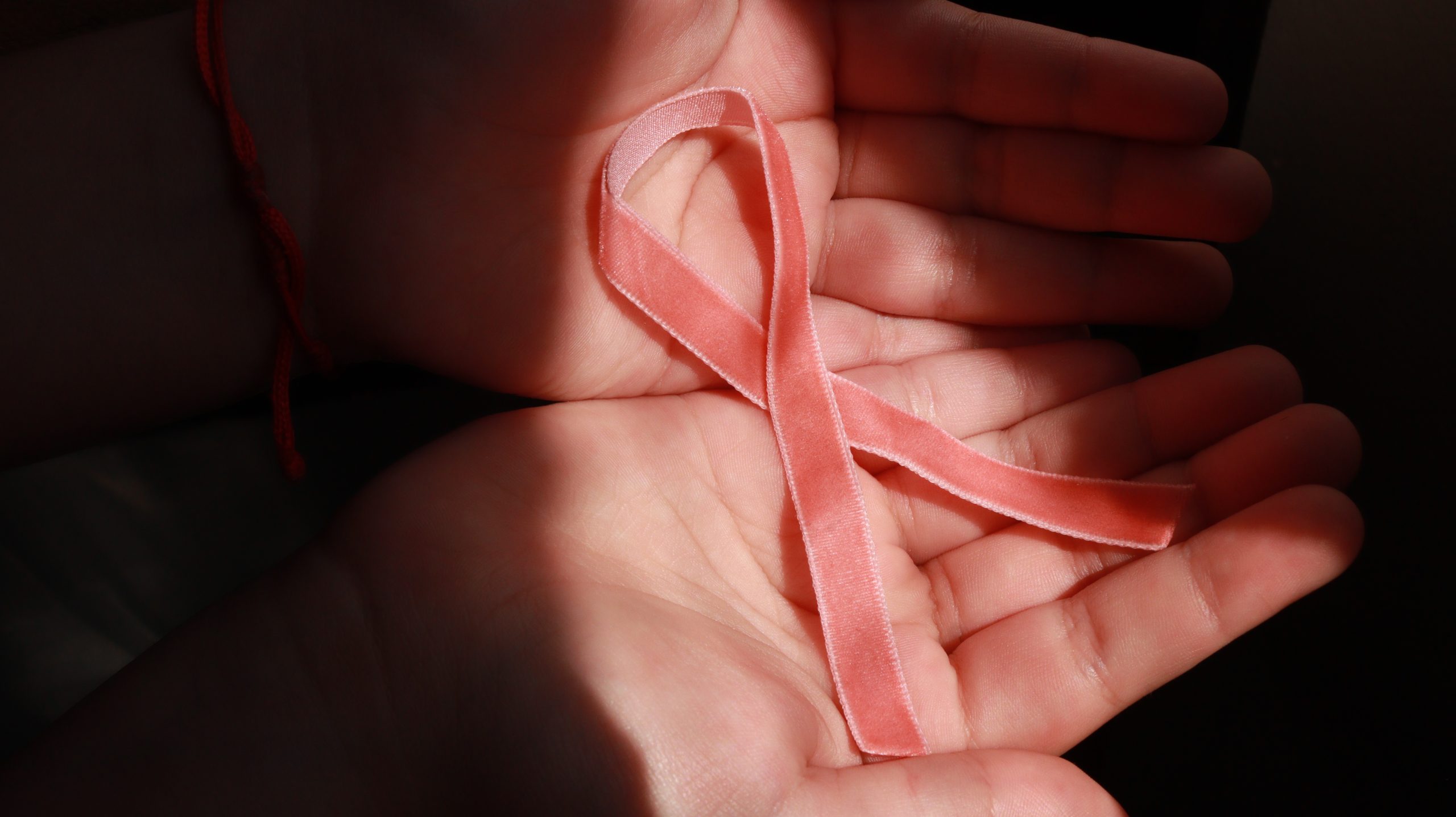 Mão segunda um laço cor de rosa, em alusão ao outubro rosa